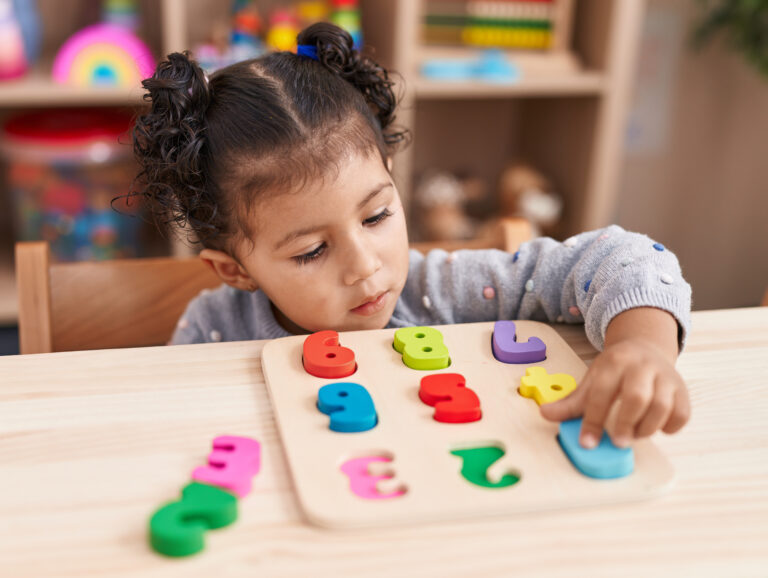 adorable hispanic girl playing with maths puzzle game sitting table kindergarten 768x578